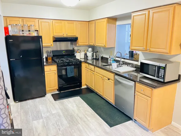 a kitchen with stainless steel appliances granite countertop a refrigerator a sink dishwasher a stove and a dining table with wooden floor