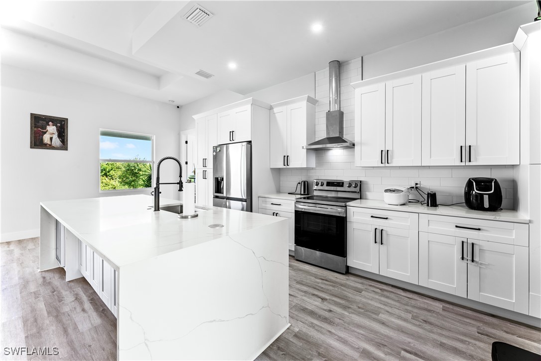 3002 42nd Street Southwest Lehigh Acres, FL 33976 - Photo 8 of 25 a kitchen with stainless steel appliances kitchen island granite countertop a stove a sink and white cabinets