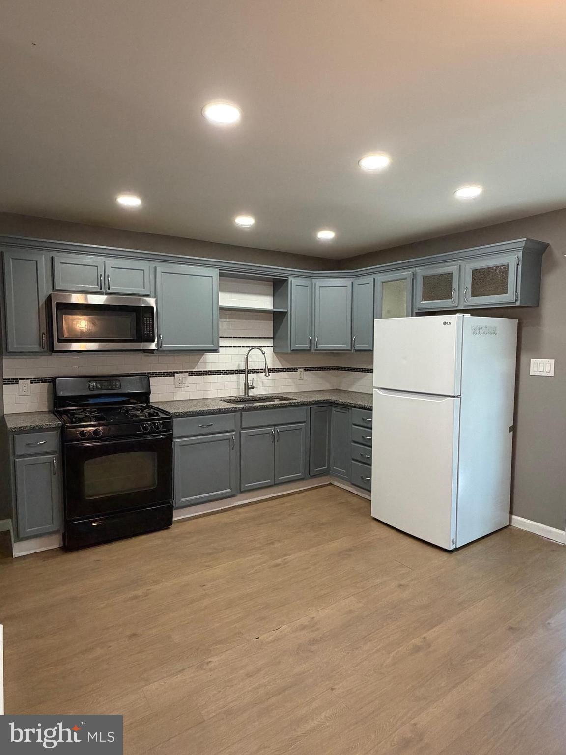 1353 Cambria Street Baltimore, MD 21225 - Photo 8 of 23 a kitchen with a refrigerator a stove top oven and white cabinets