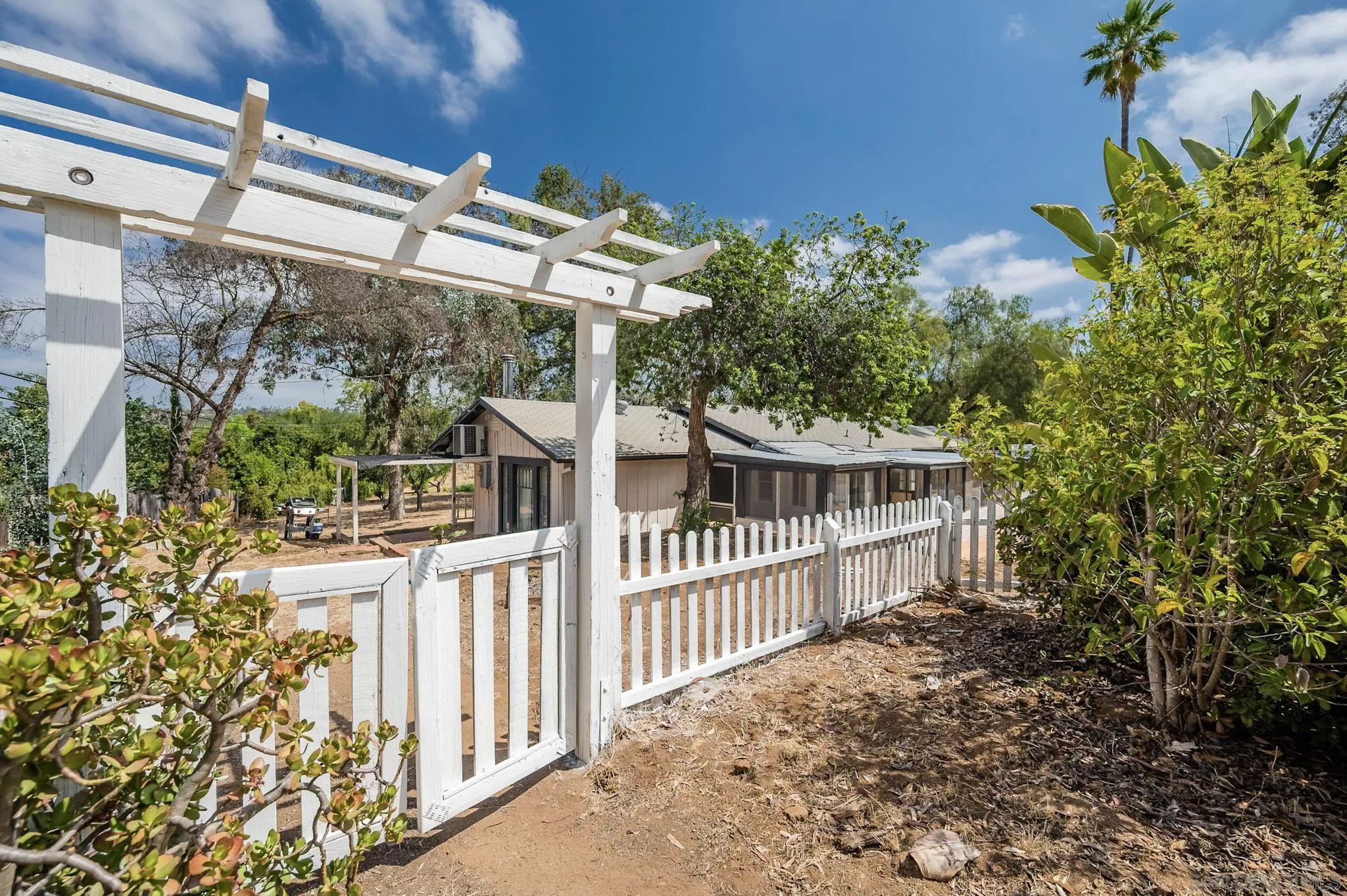 1367 Green Canyon Road Fallbrook, CA 92028 - Photo 26 of 42 a view of a house with a small yard and floor to ceiling window and wooden fence