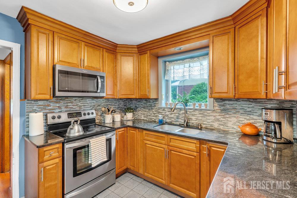 6 Carpender Road New Brunswick, NJ 08901 - Photo 15 of 30 a kitchen with stainless steel appliances granite countertop wooden cabinets a stove a sink and a microwave