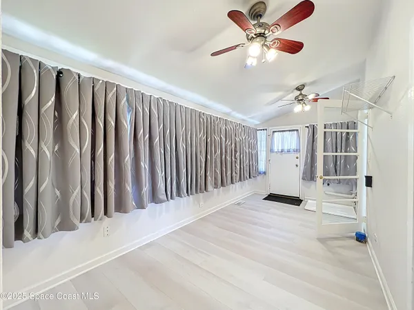 a view of wooden floor and a chandelier fan in a room