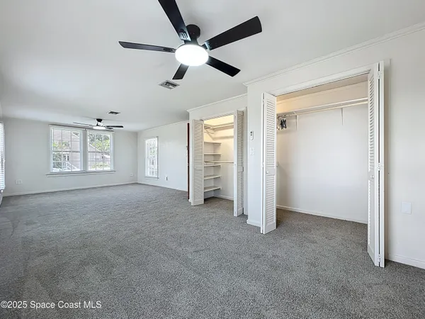 an empty room with windows and fan