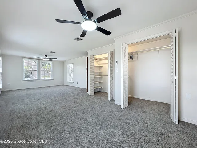an empty room with windows and fan