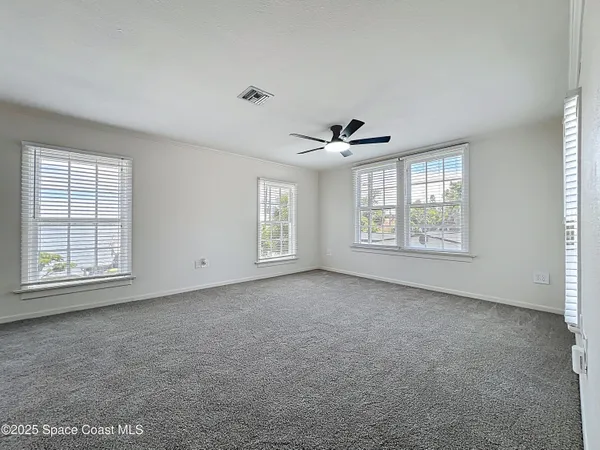 an empty room with windows and ceiling fan