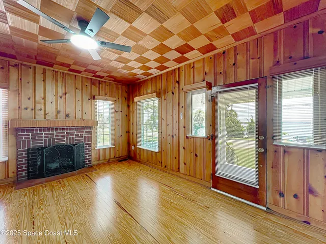 a view of an empty room with wooden floor fireplace and a window