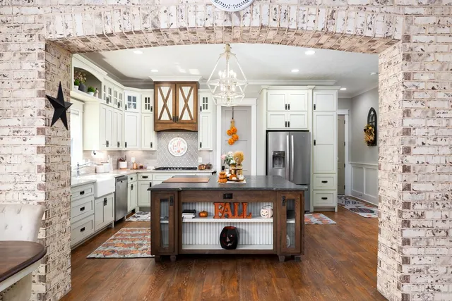 a living room with stainless steel appliances kitchen island granite countertop furniture a fireplace and a chandelier