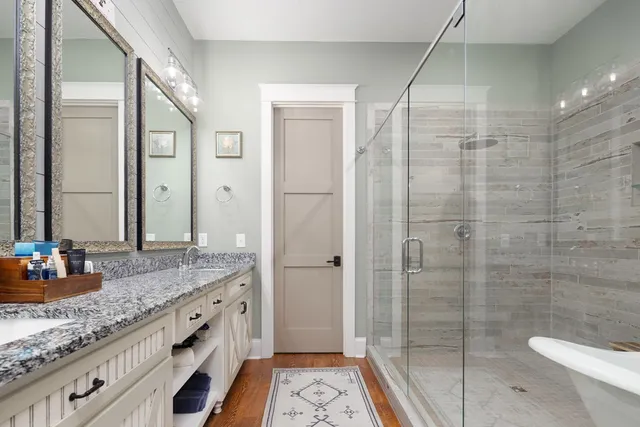 a bathroom with a granite countertop sink a mirror and shower
