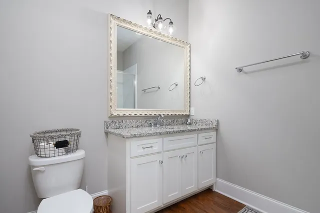 a bathroom with a granite countertop toilet a sink and a mirror