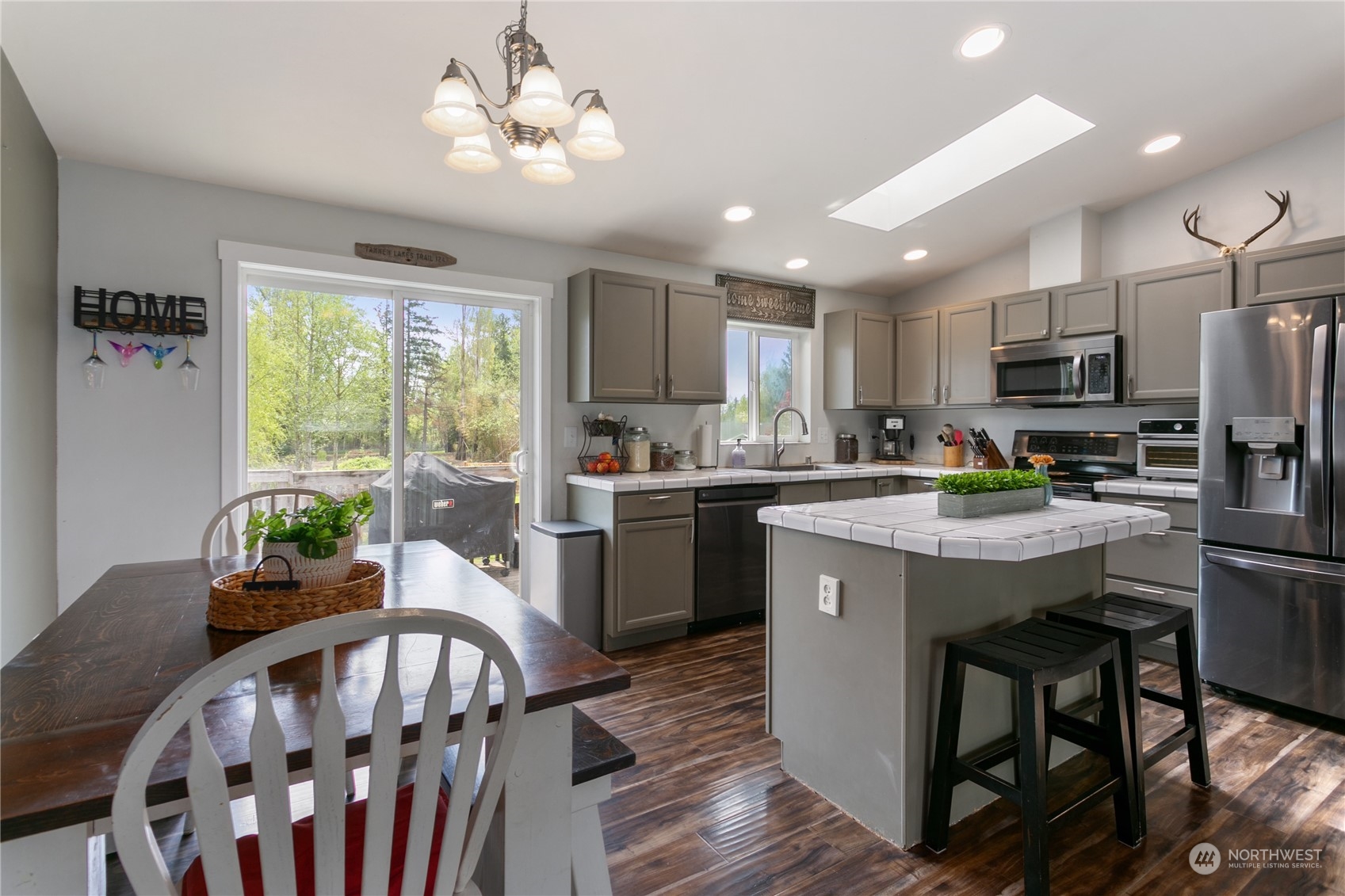 310 Allison Way Nooksack, WA 98276 - Photo 6 of 35 a kitchen with microwave a stove a sink dishwasher a dining table and chairs with wooden floor
