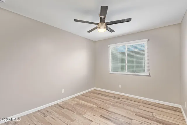 a view of empty room with wooden floor and fan