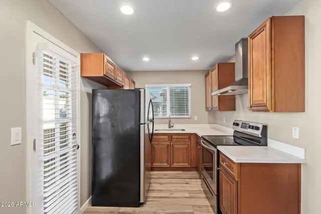 a kitchen with stainless steel appliances granite countertop a refrigerator a sink a stove and a refrigerator