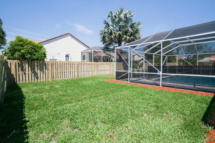 9721 Enchanted Pointe Lane Boca Raton, FL 33496 - Photo 23 of 25 a view of a backyard with wooden fence and a tree