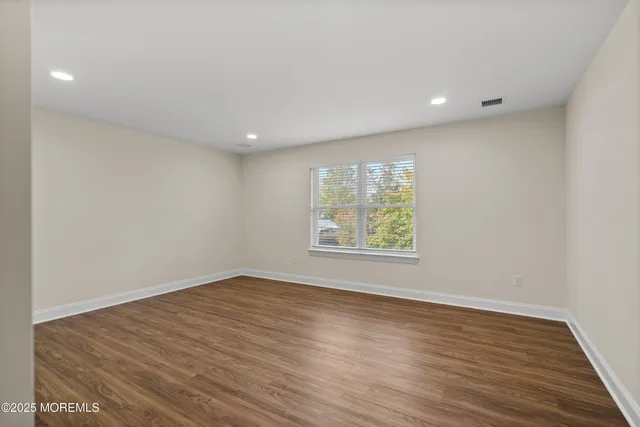 an empty room with wooden floor and window