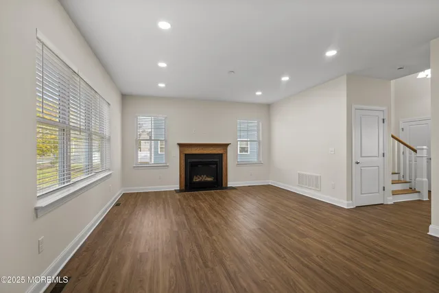 an empty room with wooden floor fireplace and windows