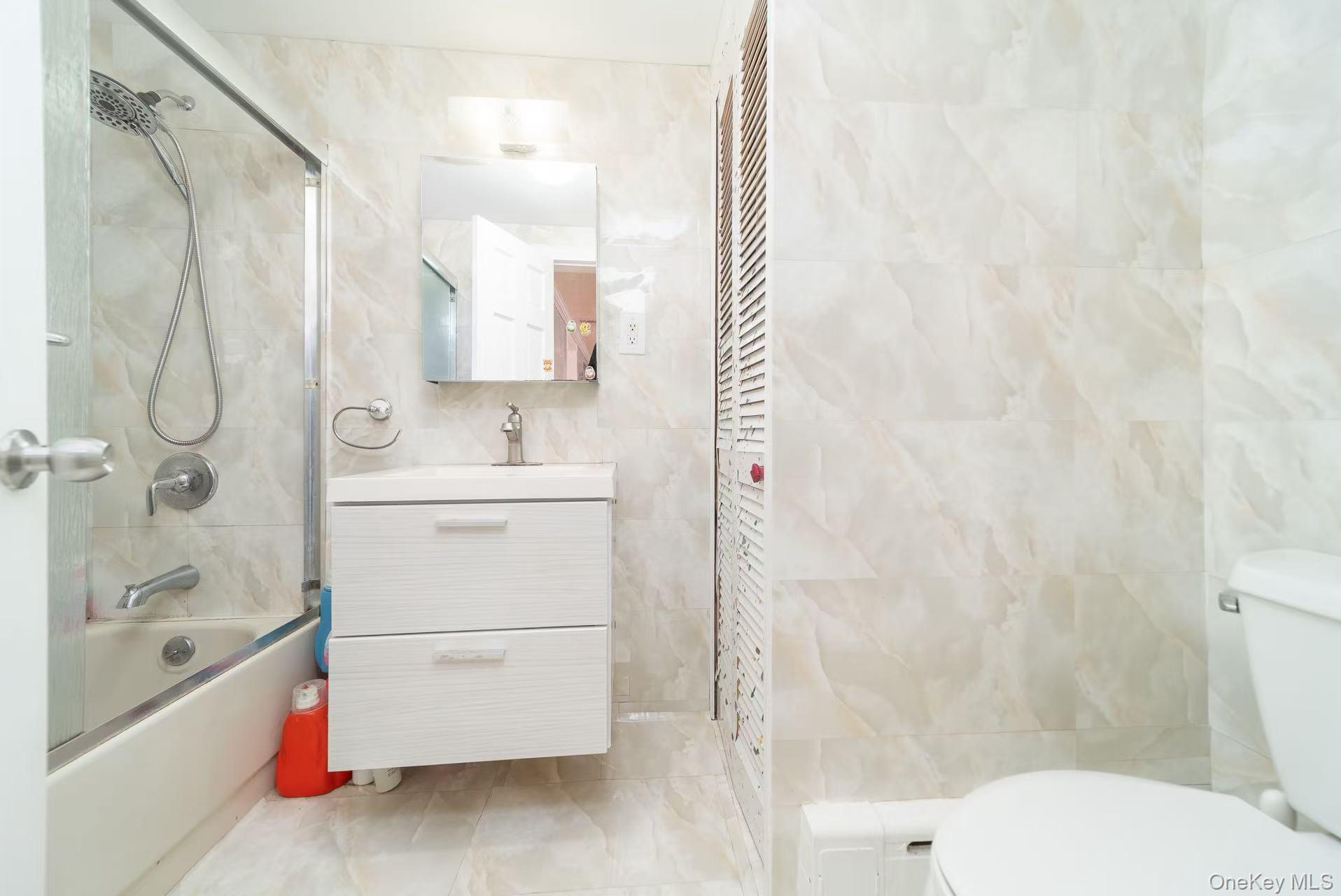 10 Church Street Queens, NY 11414 - Photo 12 of 19 Bathroom featuring tile walls, vanity, and enclosed tub / shower combo