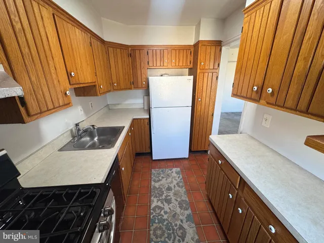a kitchen with a sink a refrigerator and a stove top oven