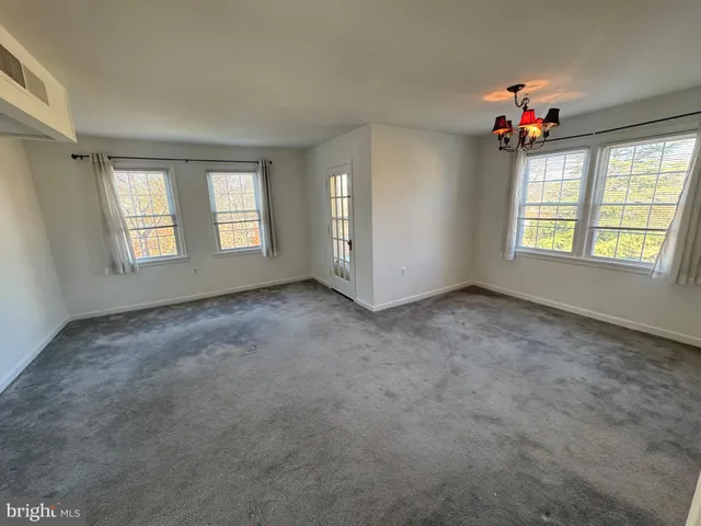 an empty room with windows and ceiling fan