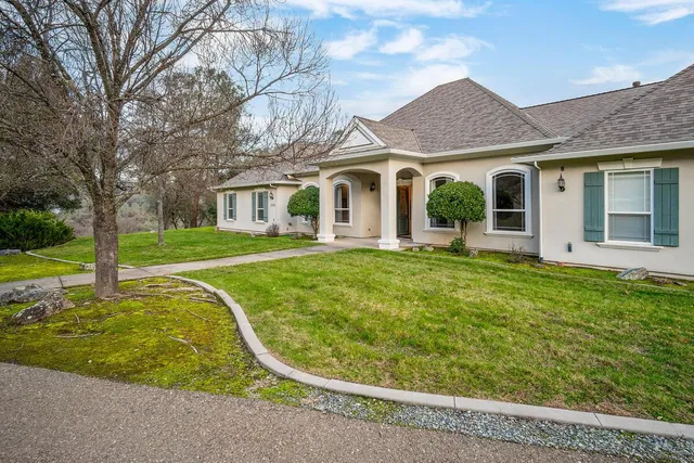a view of a white house with a small yard and potted plants