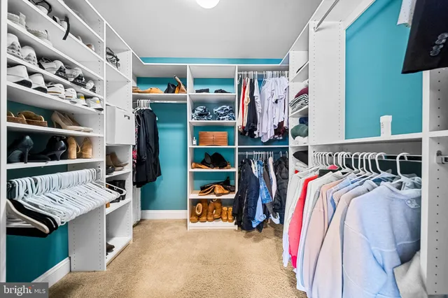 a view of walk in closet with clothes and shoes