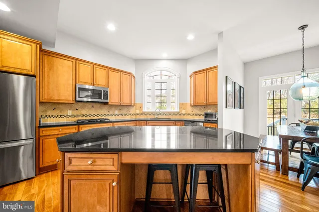 a kitchen with stainless steel appliances granite countertop a refrigerator a stove and white cabinets with wooden floors