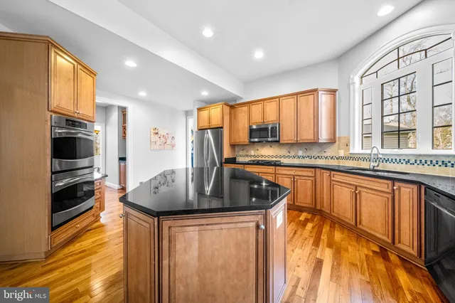 a kitchen with stainless steel appliances granite countertop a sink a stove and a refrigerator
