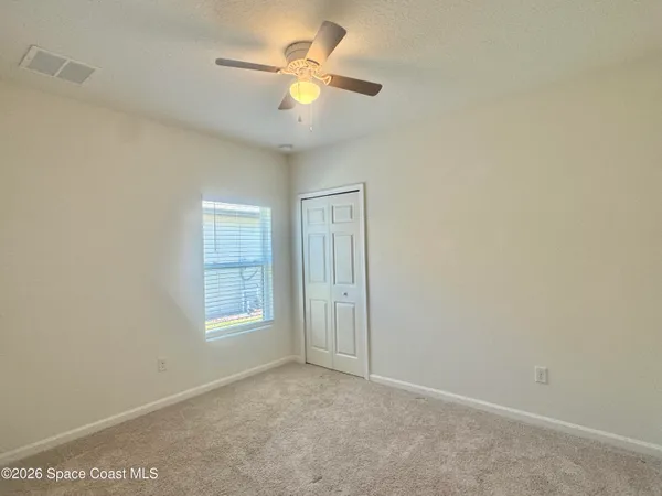 an empty room with windows and fan