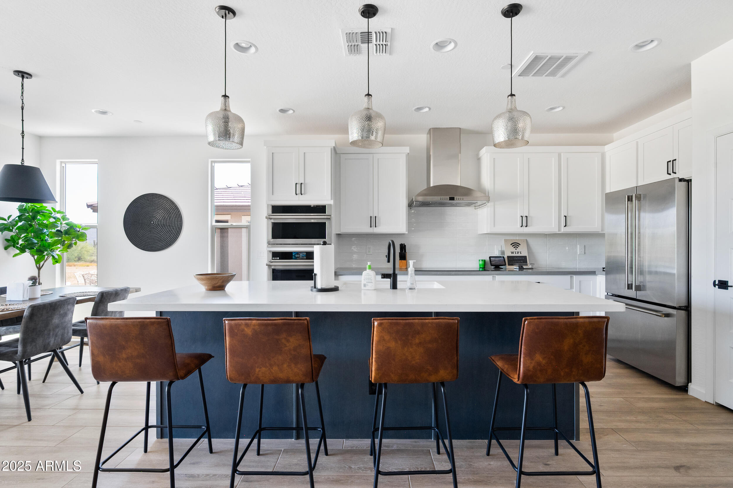 a kitchen with stainless steel appliances granite countertop a sink a stove a refrigerator and chairs with wooden floor