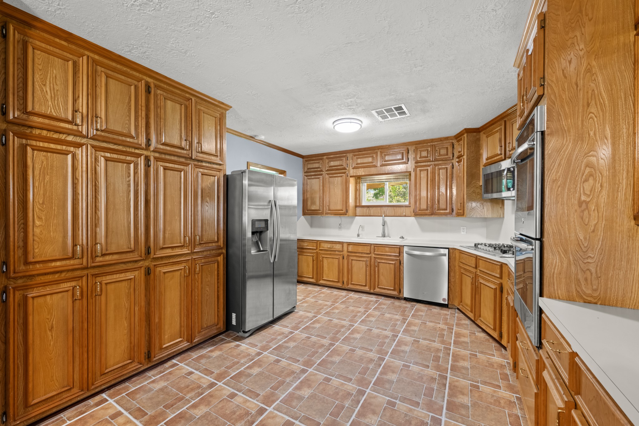 616 Cannan Drive Angleton, TX 77515 - Photo 12 of 49 Offering exceptional storage and workspace, this well-appointed kitchen features walls of custom cabinetry, generous countertops, and stainless steel appliances. The functional layout, abundant storage solutions, and natural light create an inviting space designed to accommodate both everyday cooking and larger gatherings.