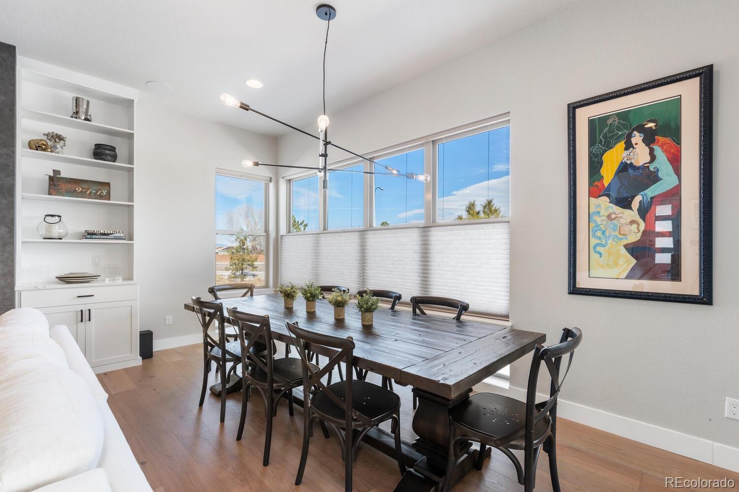 507 Red Thistle Drive Highlands Ranch, CO 80126 - Photo 6 of 42 a view of a dining room and livingroom with furniture wooden floor a rug a flat screen tv and a chandelier