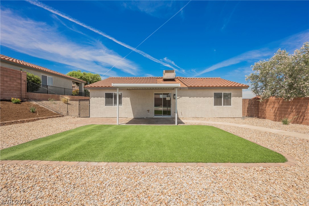 112 Iridescent Street Henderson, NV 89012 - Photo 4 of 24 A well-maintained lawn and patio area with a covered porch offers outdoor relaxation.