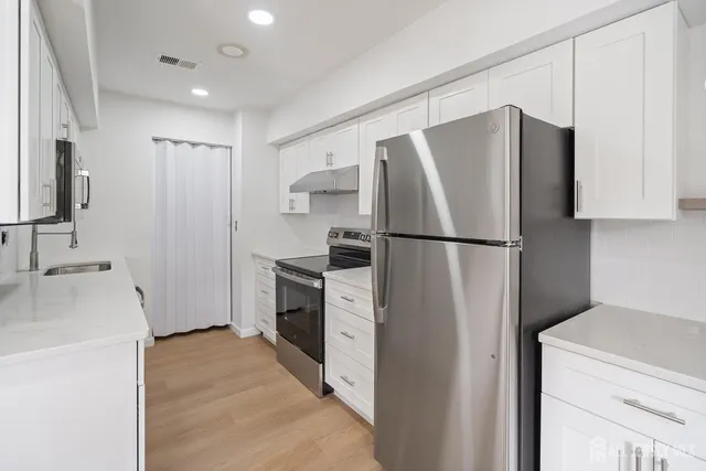 a kitchen with a refrigerator sink stove and cabinets