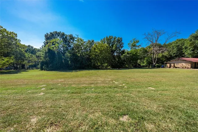 a view of a green field with trees in the background