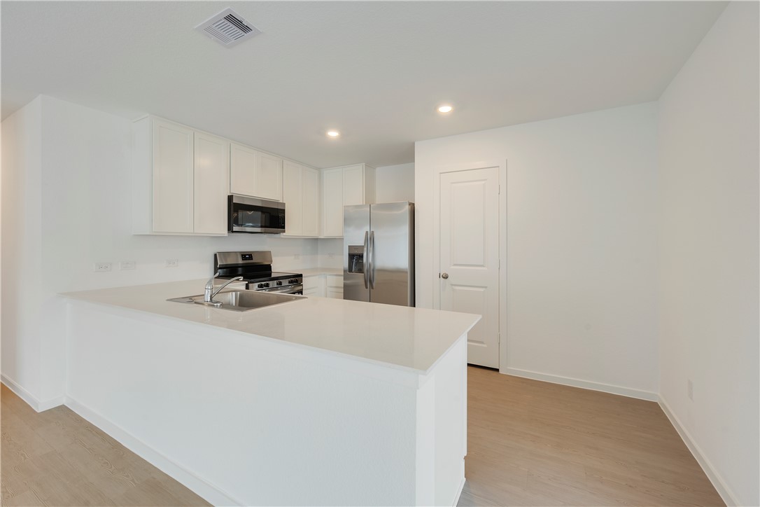 5433 Bear Run Bryan, TX 77807 - Photo 8 of 23 a kitchen with kitchen island a sink stainless steel appliances and white cabinets