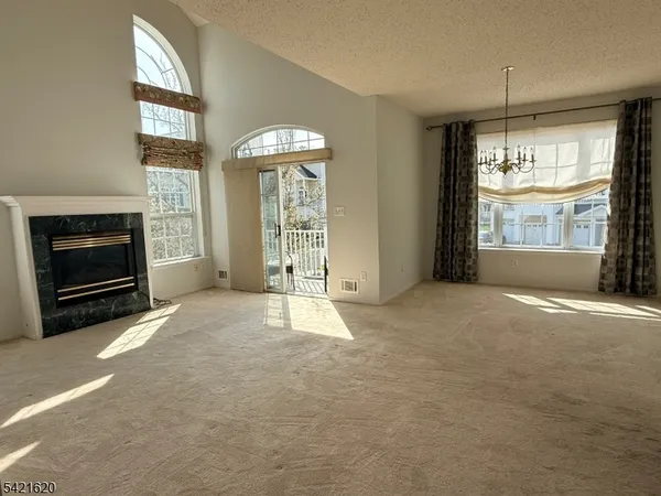a view of an empty room with wooden floor fireplace and a window