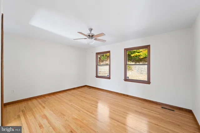 a view of an empty room with a window and wooden floor