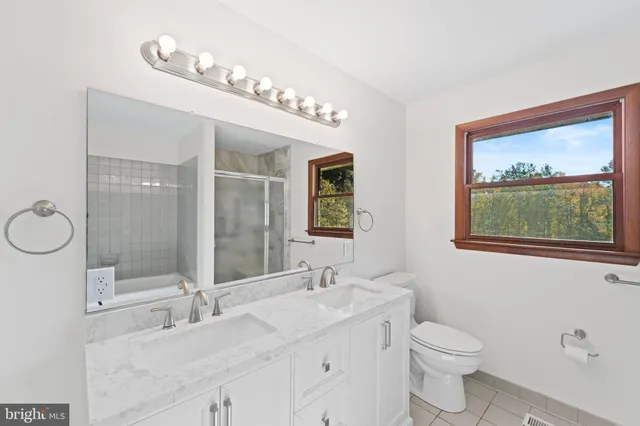 a bathroom with a granite countertop sink mirror and toilet