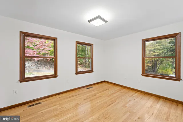 a view of an empty room with a window and wooden floor