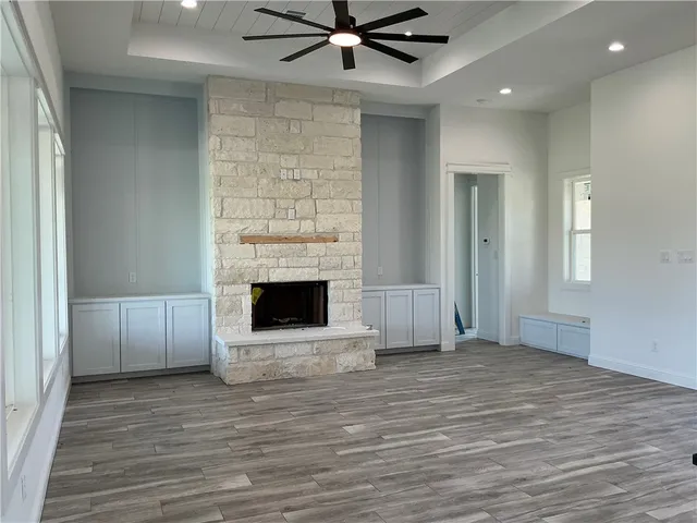 a view of a livingroom with a fireplace a ceiling fan and windows