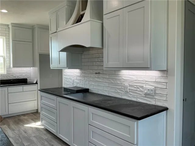 a kitchen with granite countertop white cabinets and sink