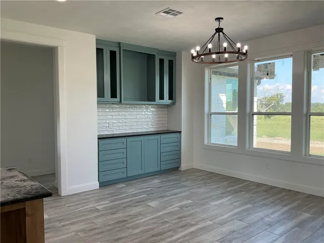 a large kitchen with stainless steel appliances granite countertop a stove and a wooden floors