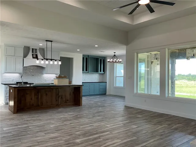 a large kitchen with stainless steel appliances granite countertop a large counter top a stove and a wooden floors