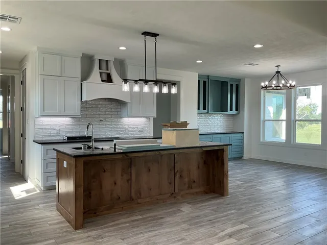 a large kitchen with stainless steel appliances granite countertop a stove and a wooden floors