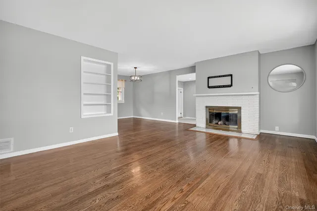 an empty room with wooden floor fireplace and windows