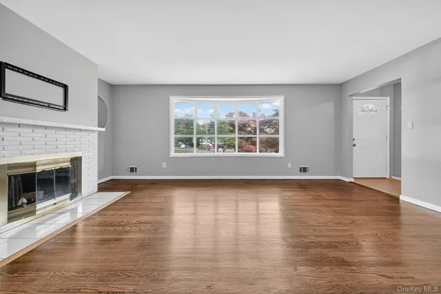 a view of empty room with wooden floor and fireplace