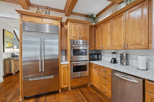 a kitchen with a sink dishwasher a dining table and chairs with wooden floor
