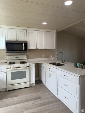 446 Riverside Drive, Unit 24 Wellington, UT 84542 - Photo 6 of 14 Kitchen with white gas range oven, stainless steel microwave, white cabinetry, recessed lighting, and light wood-style flooring