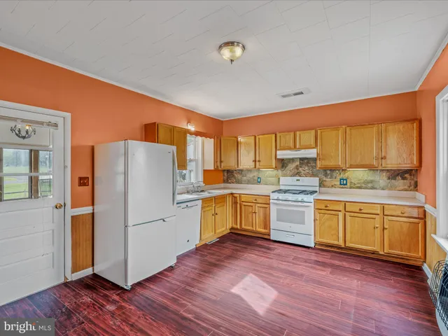 a kitchen with a refrigerator wooden floor and white cabinets