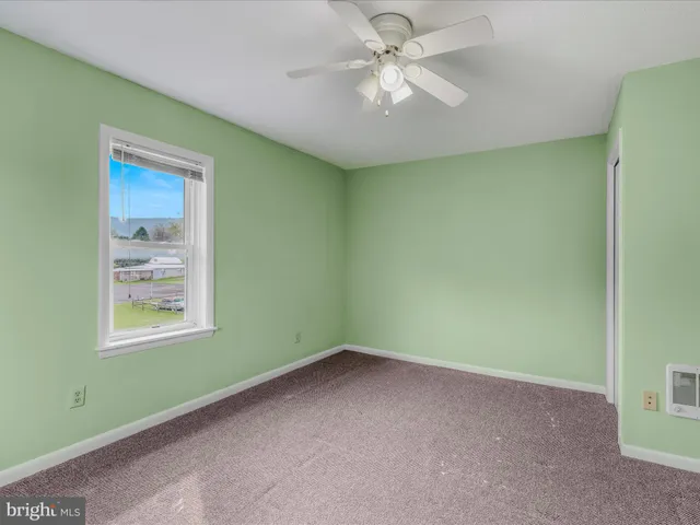 an empty room with a window and a fan