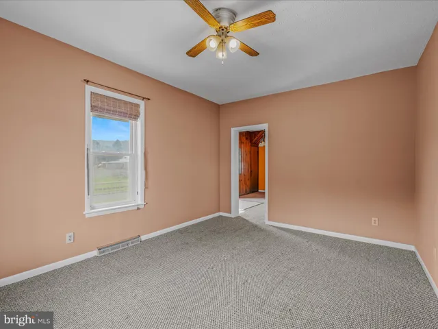 an empty room with closet and a ceiling fan